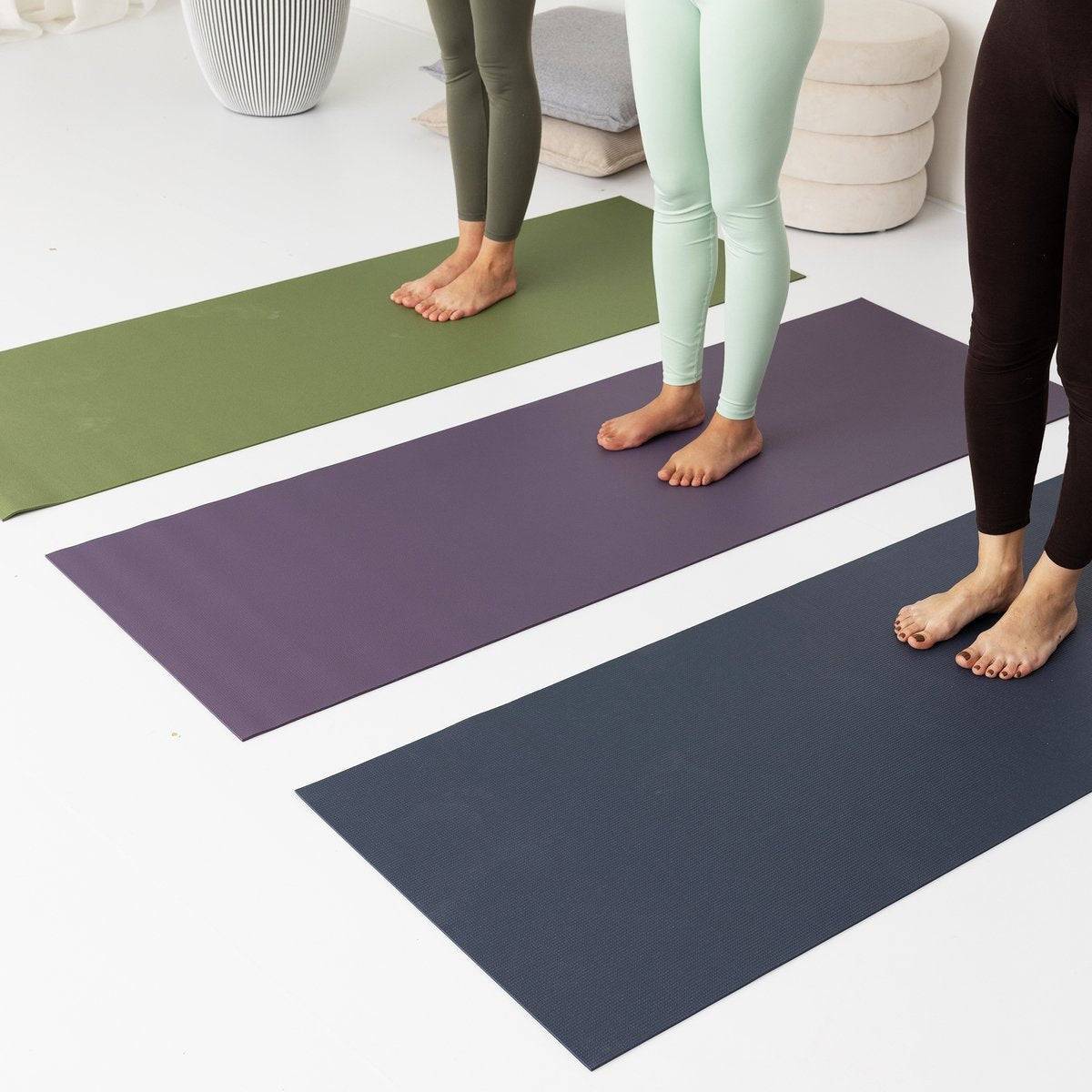 two women standing on yoga mats in a room