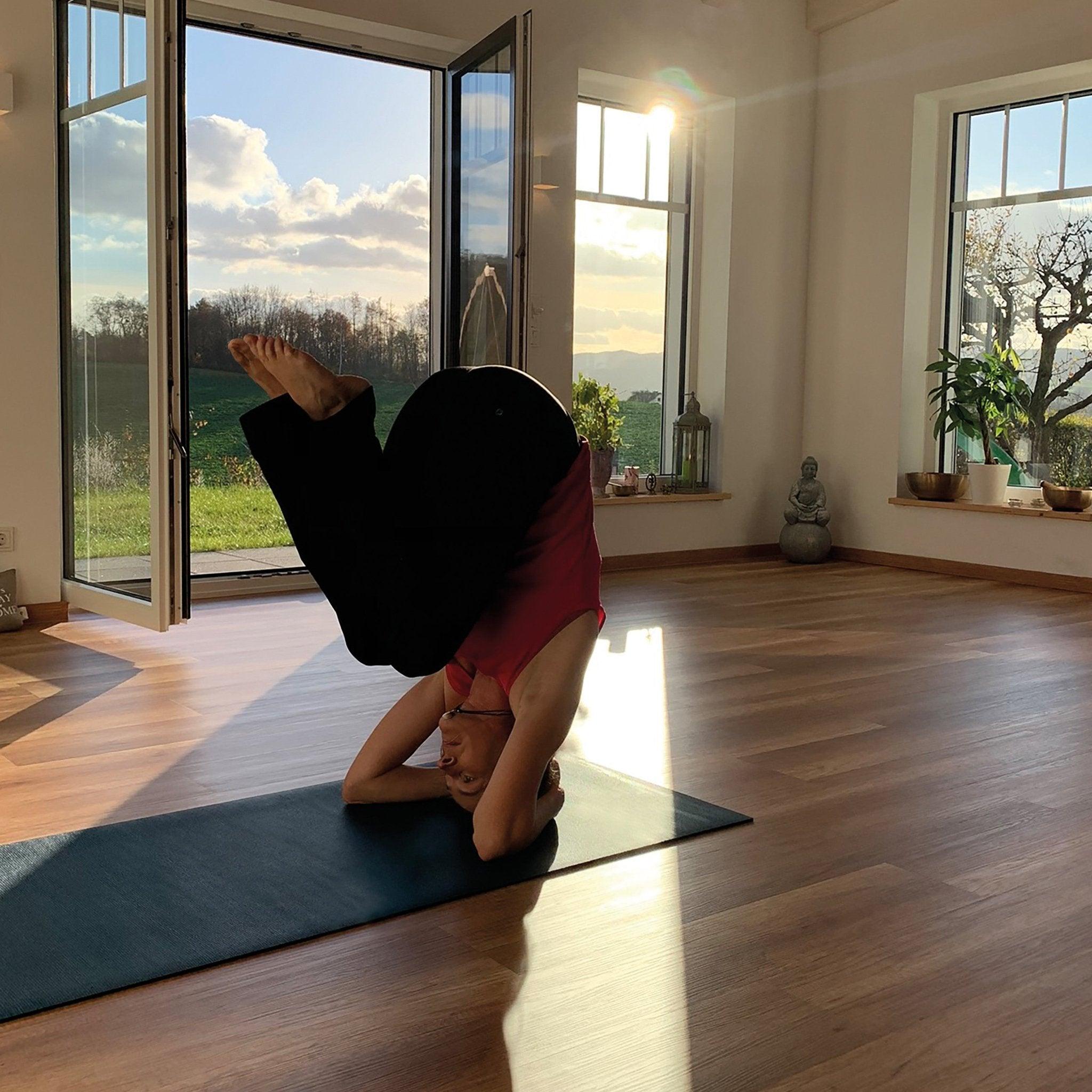 a person doing a handstand on a yoga mat