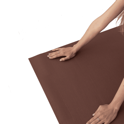 a woman stretches her hands on a yoga mat