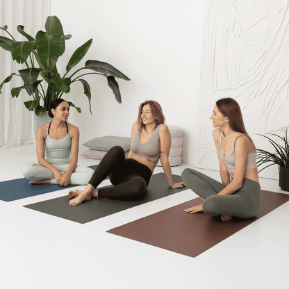 a group of women sitting on yoga mats in a room